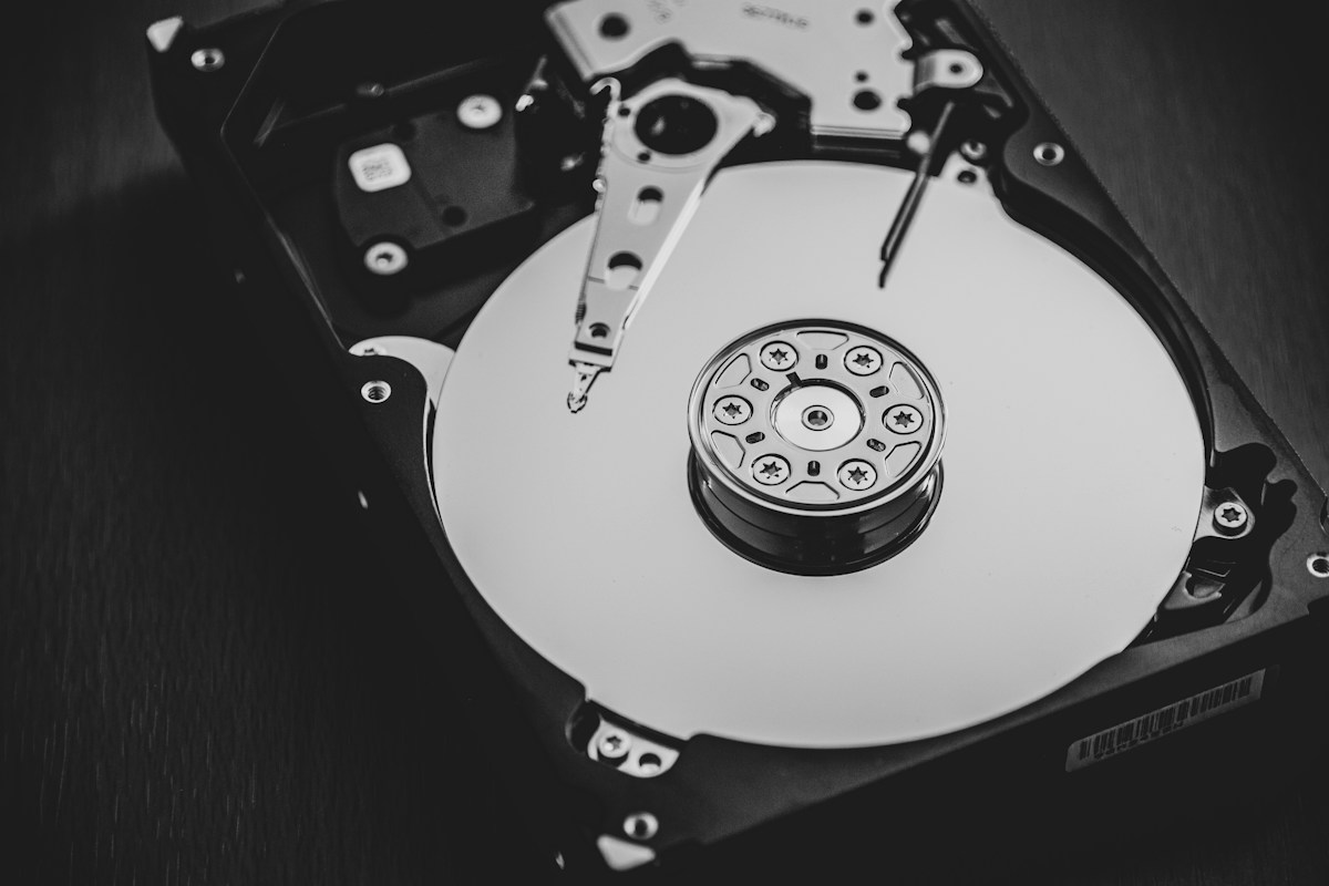 Disco duro mecánico sobre superficie neutra con sus componentes magnéticos expuestos — Fotografía por Denny Müller en Unsplash